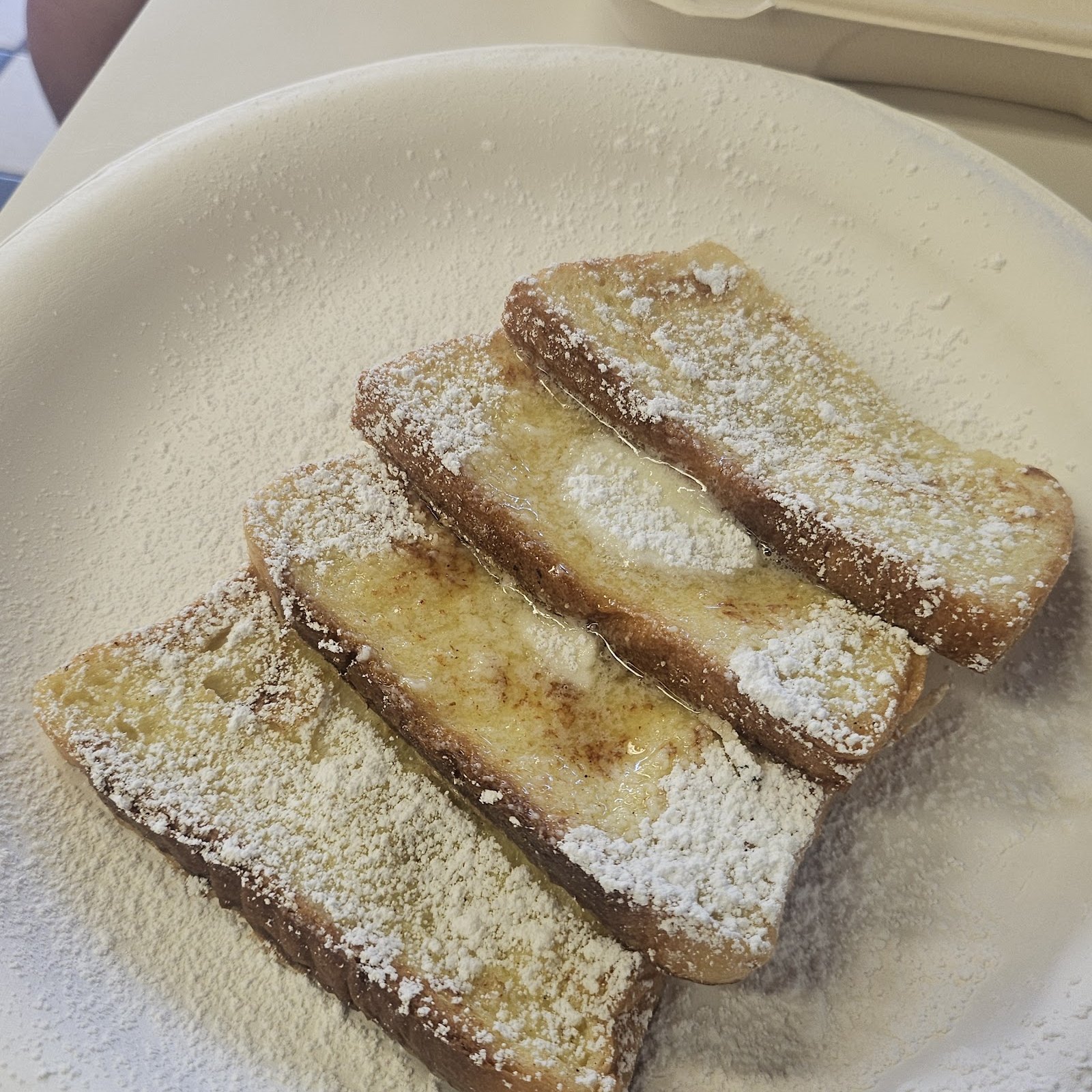 A plate of golden French toast dusted with powdered sugar.